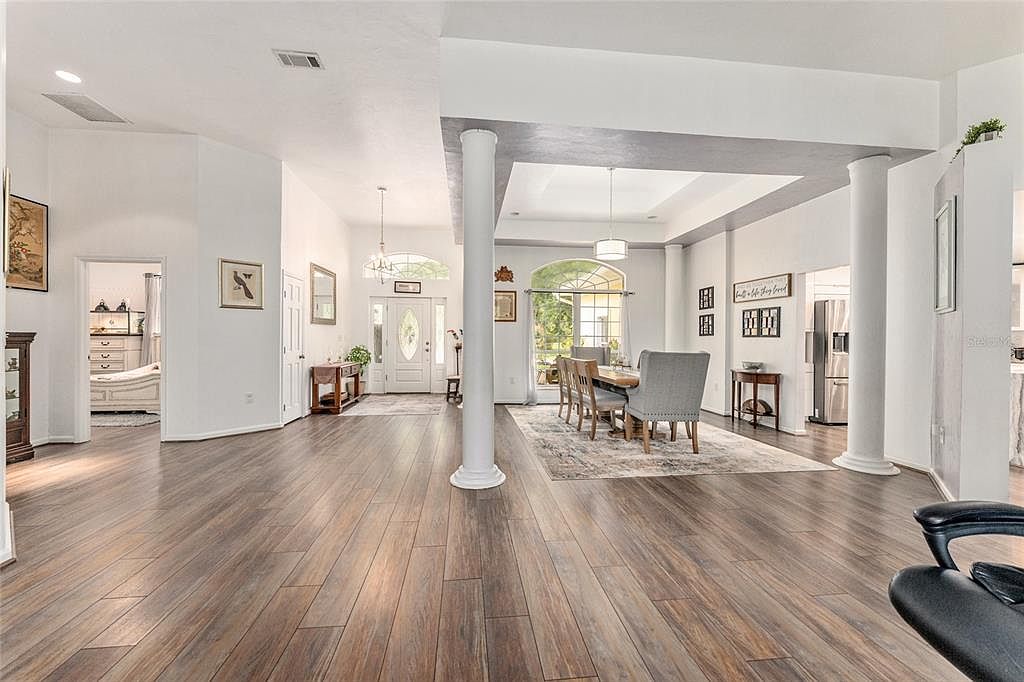 The entry foyer with white columns opening to the dining room and the great room beyond