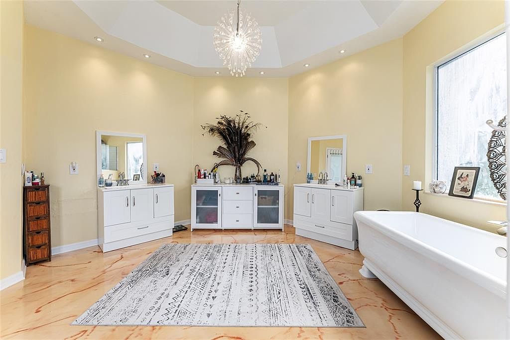 The spa primary bath with a freestanding tub, dual vanities, and a starburst crystal chandelier in the domed ceiling
