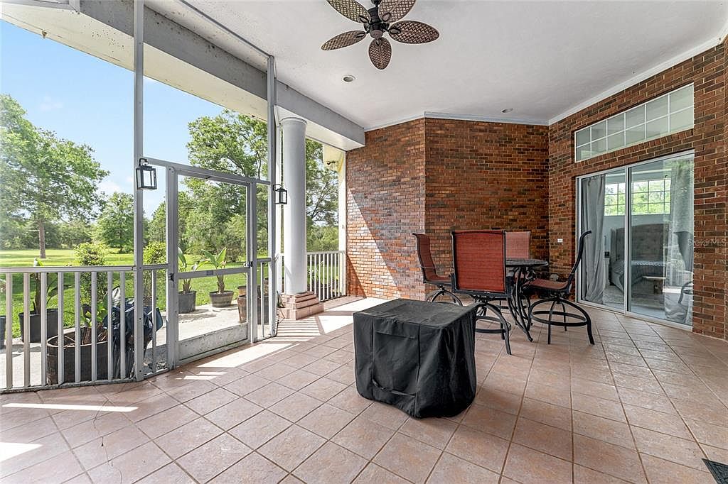 The screened-in brick lanai with a ceiling fan and direct access to the back pasture