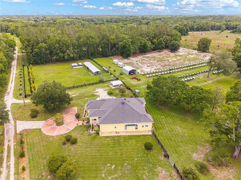 Aerial view of the wider estate with outbuildings, beehive apiary, and the long fence-line stretching back through the woodland edge